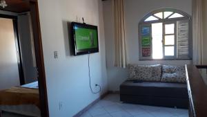 a living room with a couch and a tv on the wall at Na Brisa TEMPORADA in Mucugê