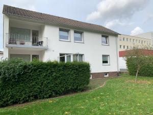 una casa blanca con un seto delante de ella en Souterrain Apartment Laatzen, en Hannover