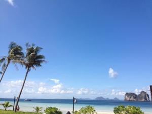 a beach with two palm trees and the ocean at Thanya Beach Resort - SHA Plus in Ko Ngai