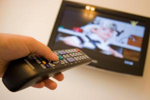una persona che tiene in mano un telecomando davanti alla televisione di Anthimos a Baile Felix