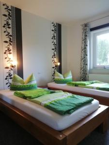 two beds in a room with green pillows at Ferienhaus Am Anger in Gustow