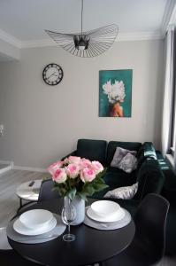 a living room with a couch and a table with pink roses at Green Park Apartament in Toruń