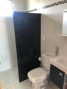 uma casa de banho com um WC e uma porta de duche preta. em Porto Cavalinho apartamento 10 em Porto de Galinhas mais 5 fotografias