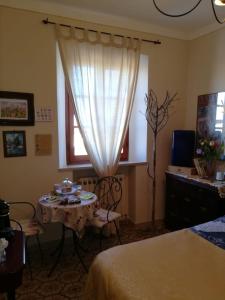 Cette chambre comprend une table et une fenêtre. dans l'établissement L'apparita Camere, à Pienza