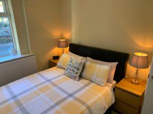 a bedroom with a bed with two lamps and a window at The Firs - Moorside Annexe in Douglas