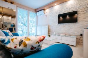 uma sala de estar com um sofá e uma televisão numa parede de tijolos em Turist Apartment em Niš