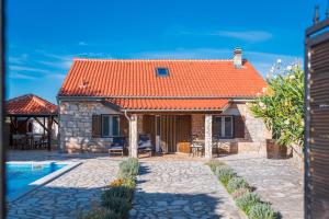 una casa con techo naranja y piscina en Rural House Gluic, en Bogatić