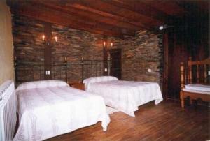 a bedroom with two beds and a stone wall at Casa Do Concello in Arnado