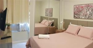um quarto com 2 camas e almofadas cor-de-rosa em FANTÁSTICO APARTAMENTO NA BARRA em Salvador