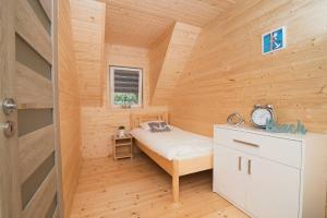 a small bedroom with a bed in a wooden room at Domki Wakacyjne Wybrzeże in Mielno