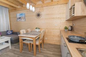 eine Küche und ein Esszimmer mit Tisch und Stühlen in der Unterkunft Domki Wakacyjne Wybrzeże in Mielno + 52 Fotos