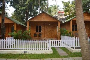 uma casa de madeira com uma cerca branca em frente em Kings Villa Resort em Palolem