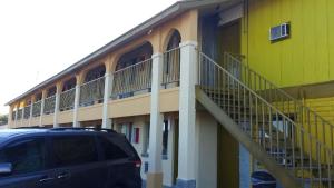 a yellow building with a staircase next to a parking lot at Carefree Inn Flatonia in Flatonia