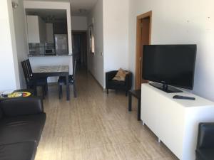 een woonkamer met een televisie en een tafel met stoelen bij alojamiento vistas al mar in Cartagena