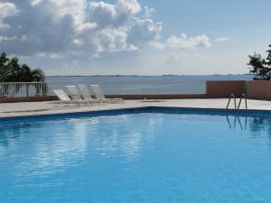 a swimming pool with chairs and a body of water at Waterfront studio at Fajardo, Puerto Rico in Fajardo
