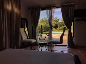 - une chambre avec un lit, des chaises et une grande fenêtre dans l'établissement Suite luxe vue sur piscine et parc, à Miramas