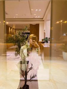un reflet d'une femme qui prend une photo dans une fenêtre dans l'établissement Grand White City Hotel, à Berat