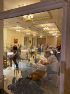 a reflection of a man sitting at a table in a restaurant at Grand White City Hotel in Berat