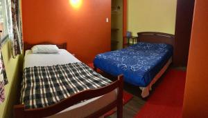 2 camas en una habitación con paredes de color naranja en Hostal Surf Olón, en Olón