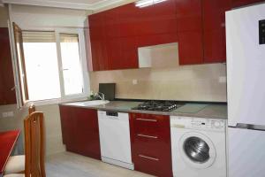 a kitchen with red cabinets and a washing machine at MARIELI in Barakaldo