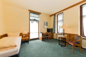 ein Hotelzimmer mit einem Bett, einem Schreibtisch und einem Fenster in der Unterkunft Hotel Katharinenhof in Werdau