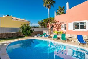 a swimming pool with chairs and a house at Villa Paraiso Spacious and Central To enjoy best beaches AC WIFI GARDEN POOL in Albufeira