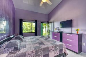 a purple bedroom with a bed and a tv at Hotel Casa Conley Del Mar in Puerto Viejo