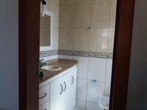 a bathroom with a sink and a toilet and a mirror at Ed. Praia de Palmas SC in Governador Celso Ramos +11 photos