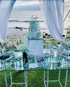 a table with a wedding cake on the beach at La Mansión Residency Suites Ensenada in Ensenada