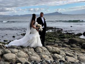uma noiva e um noivo numa praia rochosa em La Mansión Residency Suites Ensenada em Ensenada