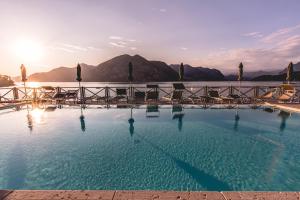 a large swimming pool with chairs and the water at Araba Fenice Hotel in Iseo +146 photos
