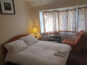 a bedroom with a white bed with a chair and a window at Elegant house 10 minutes walk to wembley stadium in London