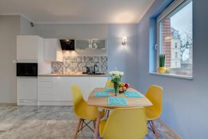 a kitchen with a wooden table and yellow chairs at Fancy Apartments Old Town in Gdańsk