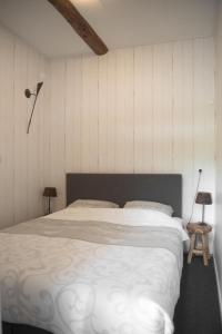 een slaapkamer met een groot bed met witte lakens bij Appartement de Berghoeve in Ruinen