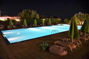 a swimming pool at night with chairs and umbrellas at Palladium Hotel in Kriopigi