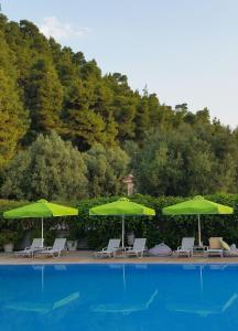 a group of green umbrellas and chairs next to a pool at Palladium Hotel in Kriopigi