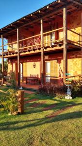a building with a porch and a bench in the grass at Pousada Canto do Rosa in Praia do Rosa