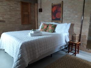 a bedroom with a large white bed with a table at Vila das Mangabeiras Corumbau in Corumbau