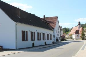 un bâtiment blanc avec un toit noir dans une rue dans l'établissement Land-gut-Hotel Forsthof, à Kastl