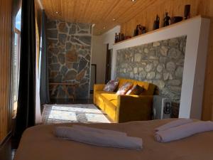 a living room with a couch and a stone wall at Guest House Keti Margiani Mestia in Mestia