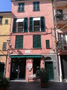 a pink building with green shutters on a street at Celle mare con posto auto coperto in Celle Ligure