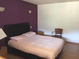 um quarto com uma grande cama branca e uma cadeira em La soulane em Ax-les-Thermes