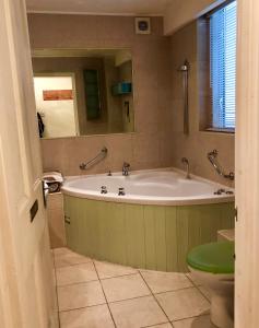 y baño con bañera, aseo y espejo. en Lauras Townhouse Apartments Grand Garden Apartment, en Bath