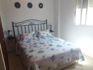a bedroom with a bed with a floral bedspread and pillows at TENERIFE HOLIDAY HOME in Candelaria