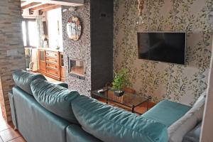 ein Wohnzimmer mit einem blauen Sofa und einem TV in der Unterkunft Casa El Simancón in Grazalema
