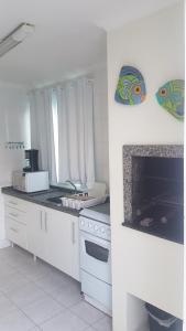 cocina blanca con fogones y fregadero en Duplex D Agostini, en Bombinhas