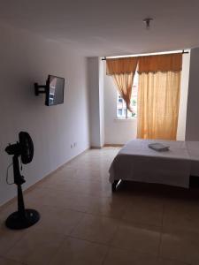 1 dormitorio con 1 cama, TV y ventana en Estadia del Lili, en Cali