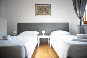 2 camas con sábanas blancas y una mesa en una habitación en B&B Foroni 29, en Verona