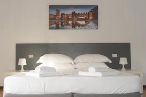 ヴェローナにあるB&B Foroni 29の白いベッド(枕2つ付)と橋の絵