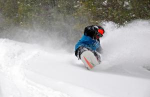 a man riding a snowboard down a snow covered slope at Massanutten's Woodstone Meadows by TripForth in McGaheysville